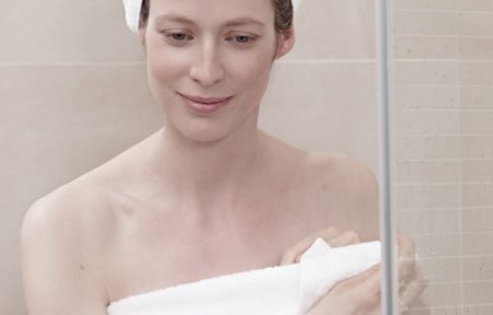 Mulher depois do banho, enrolada numa toalha e com uma toalha na cabeça.