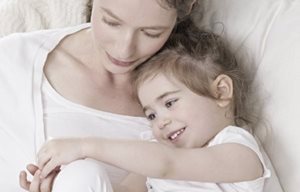 Mãe e filho deitado perto um do outro, abraçando.