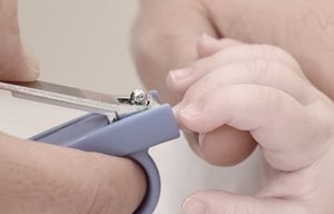 Mãe a cortar as unhas à criança com um corta unhas.