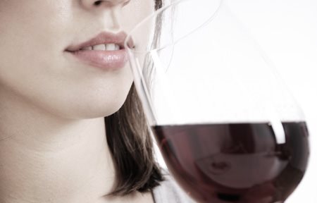 Mulher a beber um copo de vinho tinto.