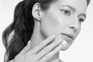 Mulher tocando com a mão no rosto.