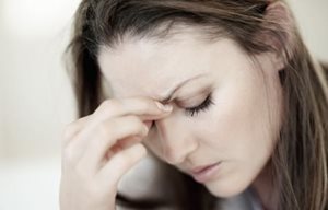 Mulher olhando para baixo, pose de stress - com a mão a tocar na testa