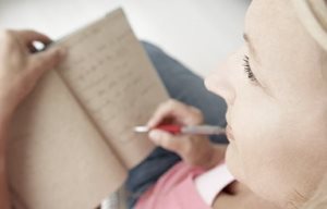 Uma mulher está a escrever algo num bloco de notas