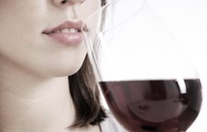 Mulher a beber um copo de vinho tinto.